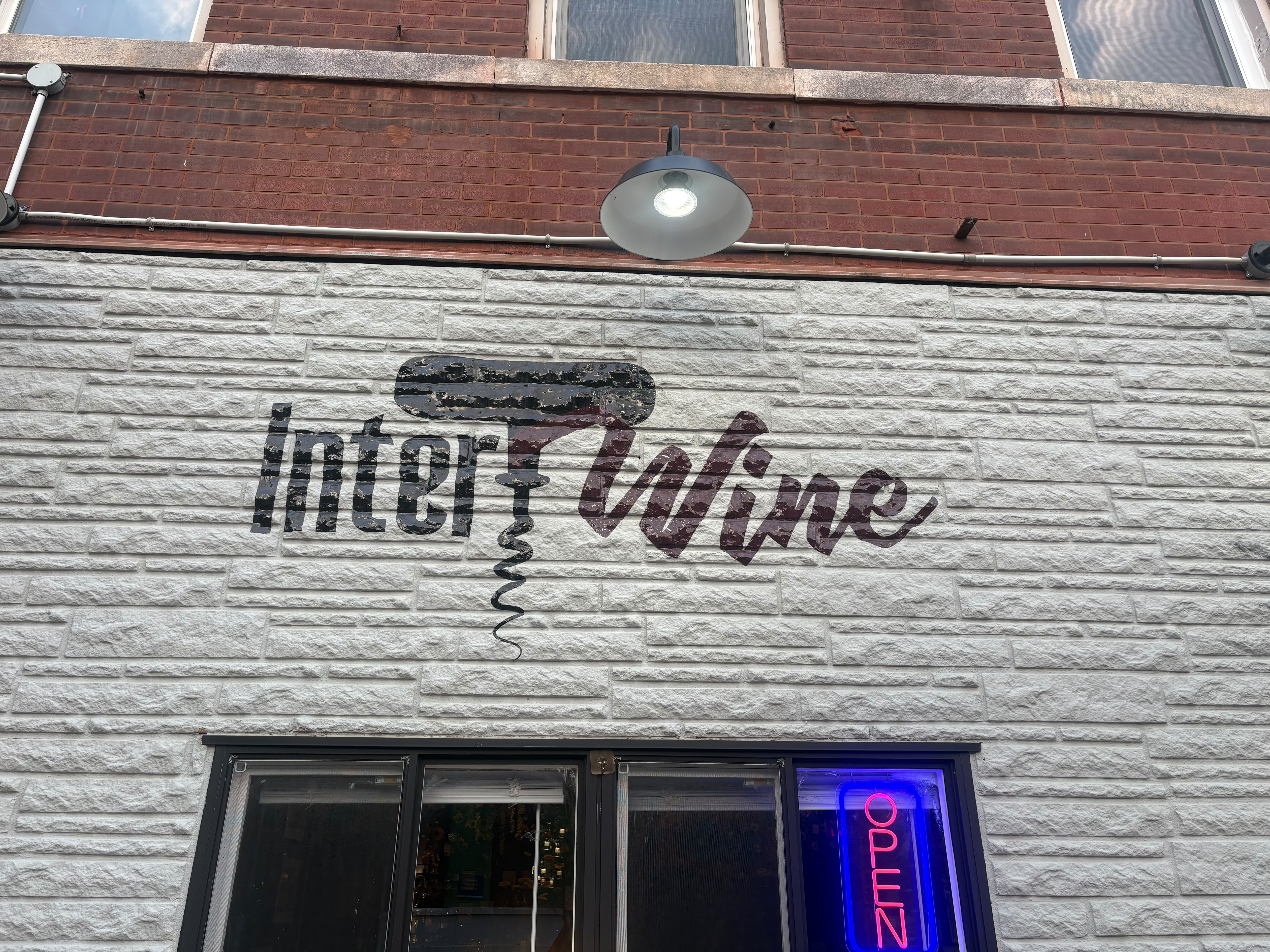 Intertwine’s painted corkscrew logo on the brick storefront above the glowing OPEN sign