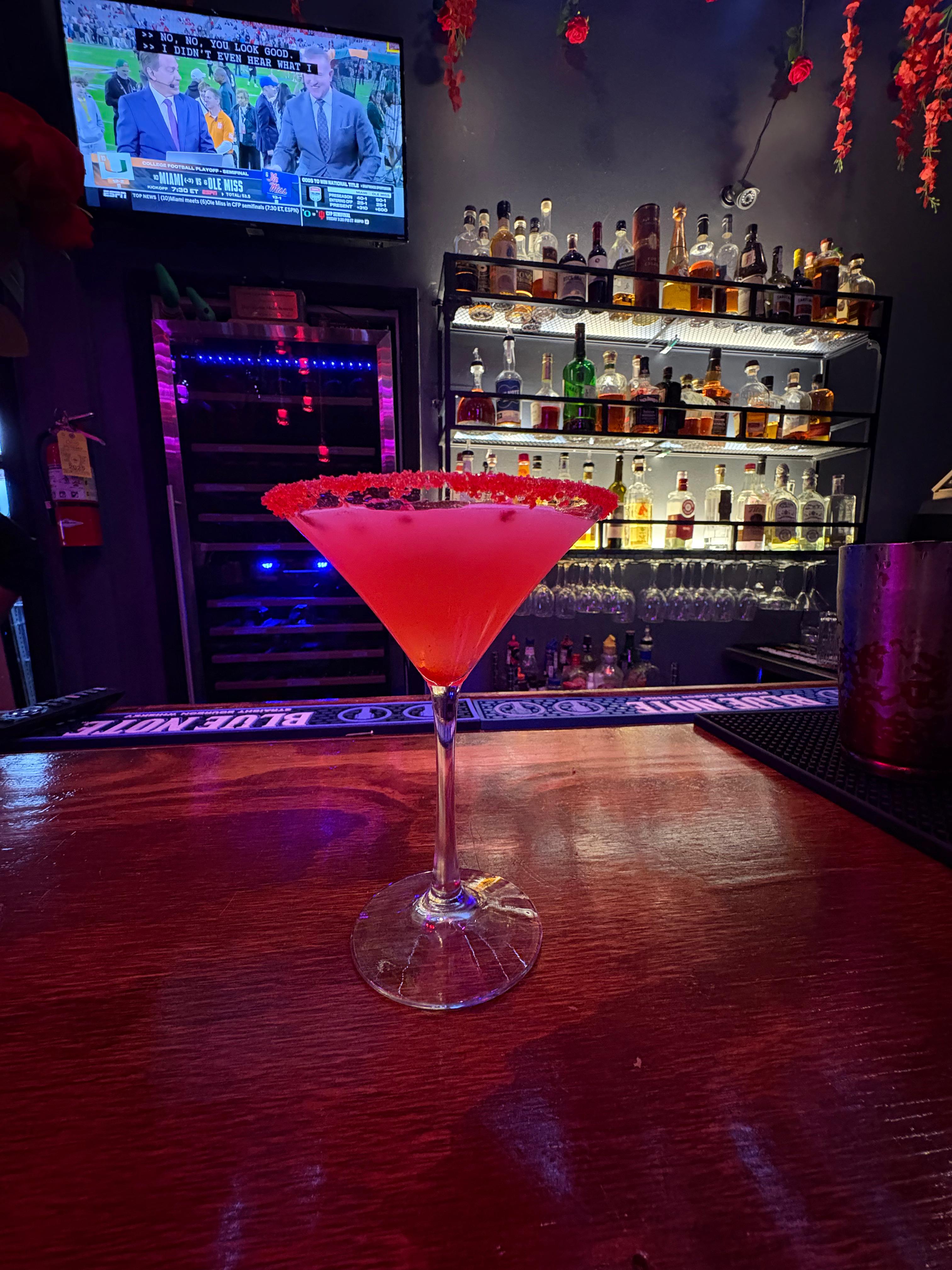 A red cocktail served against the bar backdrop